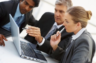 Three people looking at a laptop computer.